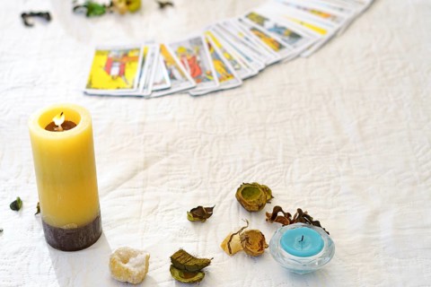 Table of a fortune teller with tarot cards, candles, quartz stones, crystal ball on a white
