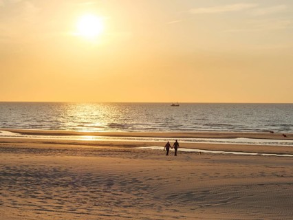 Couple walking along a quiet beach at sunset, oostende, belgium