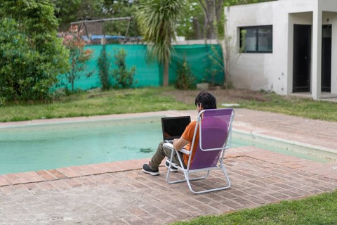Latin man working on his laptop in the pool
