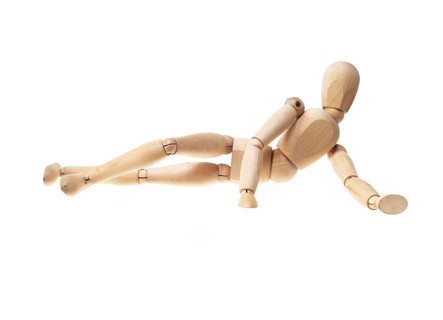 Wood mannekin laying onn side over white