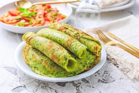 Delicious homemade ramson pancakes or crepes with tomato salad on white background