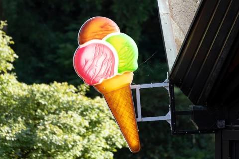 Illuminated sign in the shape of a colourful ice cream cone at an ice cream parlour in Planten un