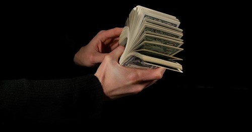 Hand of Woman and Dollar Bank Notes against Black Background