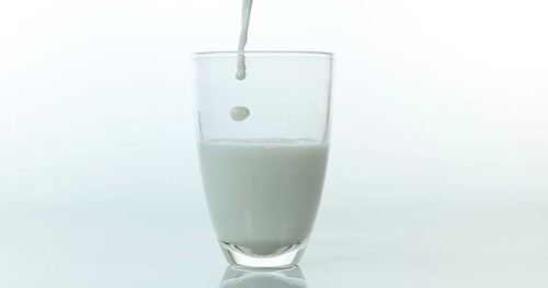 Milk being poured into Glass against White Background