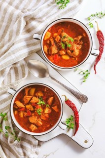Beef goulash soup - hearty Hungarian soup of meat and vegetables seasoned with paprika on white