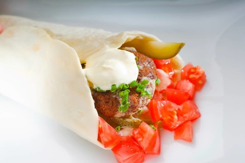 Fresh traditional falafel wrap on pita bread with fresh chopped tomatoes