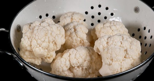 Water falling on Cauliflower (brassica) oleracea, against Black Background