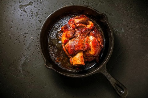 Traditional German cuisine - Roasted pork knuckle eisbein (Schweinshaxe) in iron pan on black