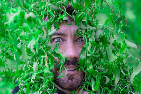 Close-up portrait of Latin man with funny expression among tree leaves