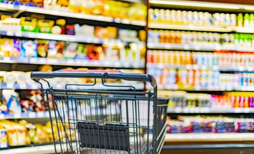 A shopping cart by a store shelf in a supermarket