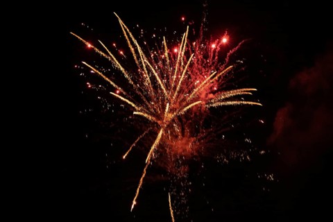 New Year's Eve fireworks night sky with golden and reddish sparks