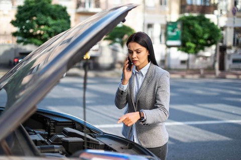 Businesswoman talking phone while her car broke down