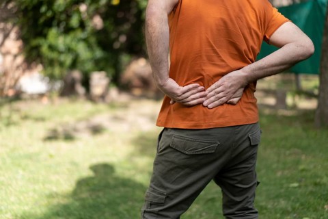 Latin man in a park massages his sore waist