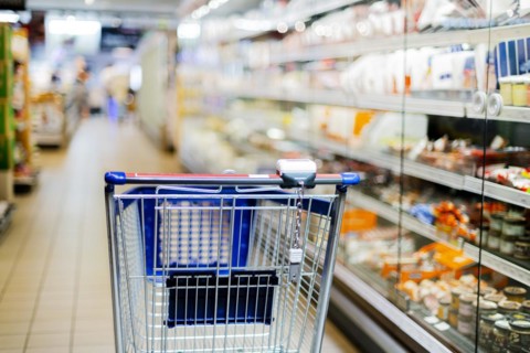 A shopping cart by a store shelf in a supermarket