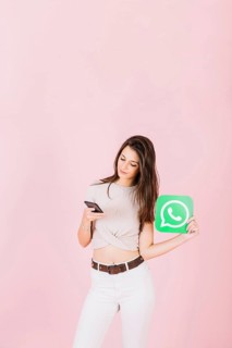Beautiful young woman holding whatsapp icon using mobile phone