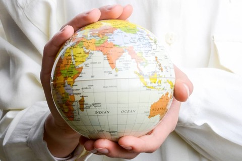 Child holding a small model globe in hand on white background