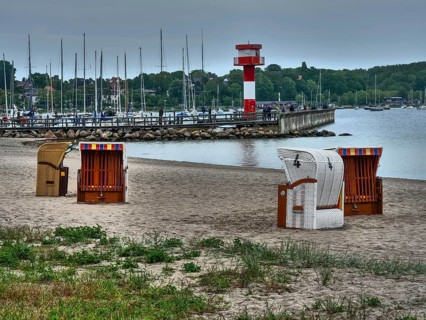 Beach with beach chairs, in the background a lighthouse and boats, overcast sky, eckernförde,