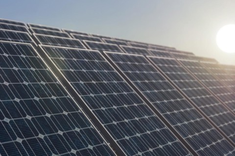 Solar power plant against the rising sun, selective focus on the first solar panel. Alternative