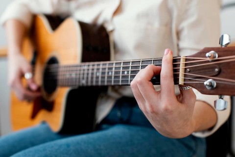 Side view female musician playing acoustic guitar