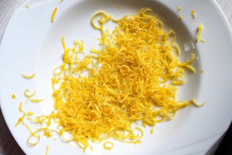 Lemon zest in a white plate, aromatic citrus peel goes well with many dishes and gives a fresh
