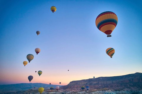 Lots of hot air balloons above fairy chimneys rock formations. Aerial view of Cappadocia. Goreme,
