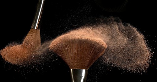 Make-up Brush spreading blush powder on black background