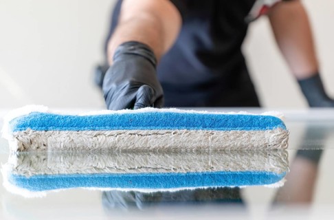 A professional window cleaner using a window cleaning washer sleeve to cleanse a large fold down