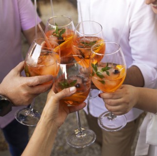 Happy friends spending time together, focus on young women drinking Aperol spritz cocktail. Summer