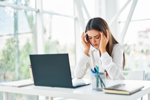 Stressed tired businesswoman sitting at her desk in modern office. Problems, pain concept