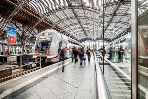 Travellers waiting for trains in a station concourse with an impressive roof, Leipzig Central