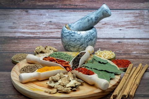 Different types of spices in wooden spoons on a wooden disk ginger, cayenne, pepper, cinnamon,