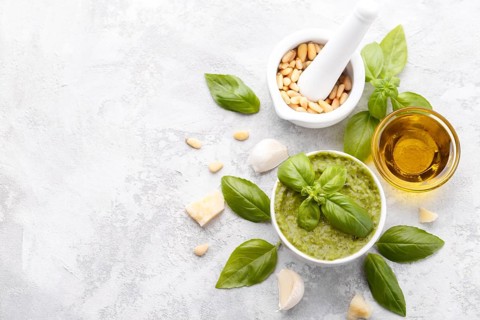 Pesto sauce and ingredients, cheese, basil, garlic, pine nuts, olive oil on grey stone background