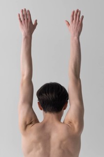 Back view naked man with arms raised