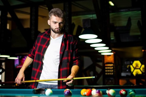 Medium shot guy with pool cue looking table