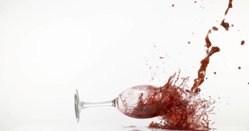 Glass of Red Wine Falling and Splashing against White Background