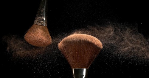 Make-up Brush spreading blush powder on black background