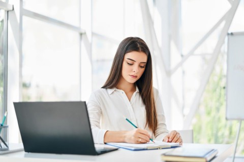 Pretty businesswoman with laptop and papers working at modern office. Woman signing contract and