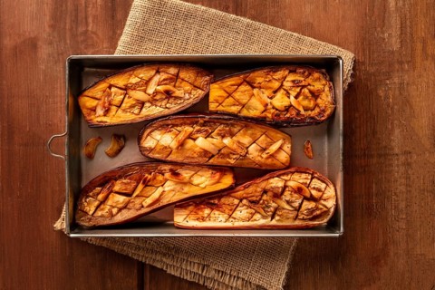 Roasted eggplants with garlic, shot from the top on a dark rustic wooden background with copy space