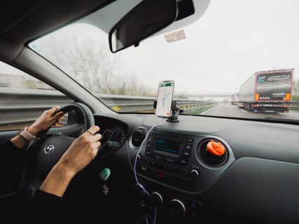 Inside view of a car with the driver's hands on the wheel and a mobile navigation system, A1 A8
