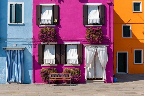 Blue, pink and yellow house facade with flowers, colourful houses, alleys on the island of Burano,