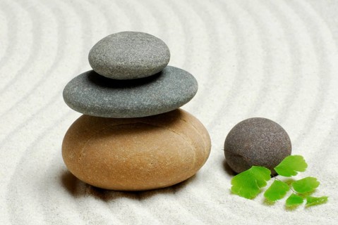 Stacked stones and leaf of lady hair fern, in sand