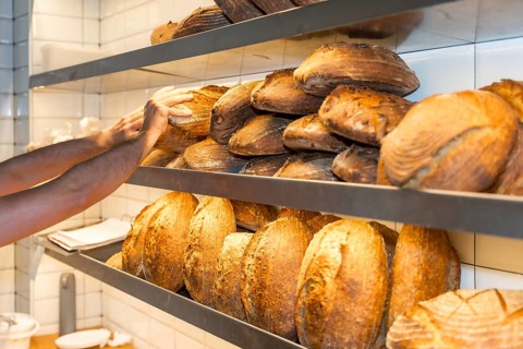 Male employee baker of bakery in the workshop workshop of artisan bakery placing the baked bread