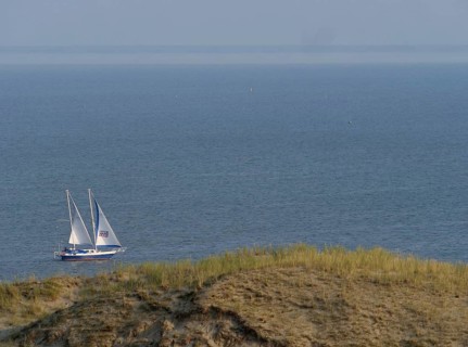 Sailboat in the Curonian Lagoon in front of the Parnidis Dune on the coast of the Curonian Spit,