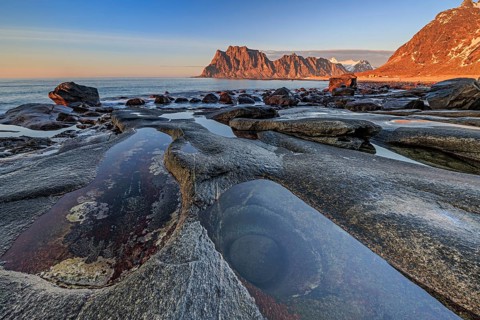 Rocky coast in front of steep mountains in the evening light, winter, the eye, Utakleiv,