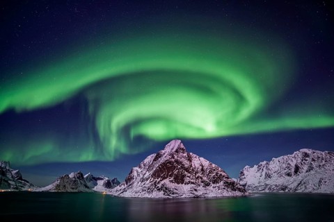 Green northern lights reflected in fjord, steep mountains, aurora borealis, winter, Reine,