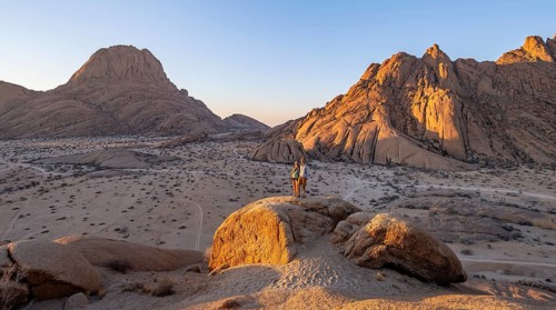 Couple on a mountain at sunset, summit of the Great Spitzkoppe and Pontoks in the background,
