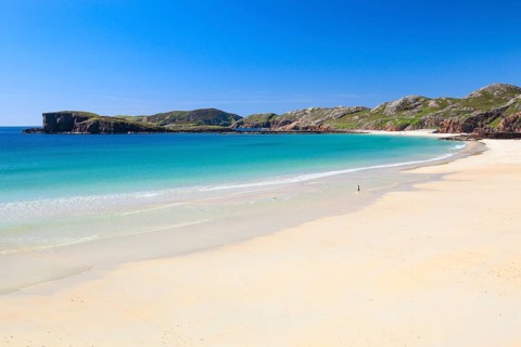 Lonely person on the idyllic sandy edge of Oldshoremore, on the west coast of Scotland