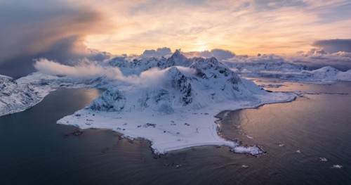 View of Flakstad and Skagsanden beach, snow-covered mountains and fjord at sunset, aerial view,