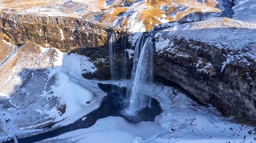 Aerial drone view of frozen Seljalandsfoss waterfall with snow in Iceland
