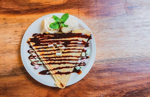 Top view of chocolate crepe with ice cream on wooden table. High angle view of chocolate crepe with